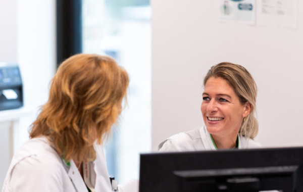 2 zorgmedewerkers met elkaar in gesprek achter pc