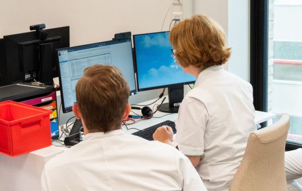 Twee zorgprofessionals achter beeldscherm