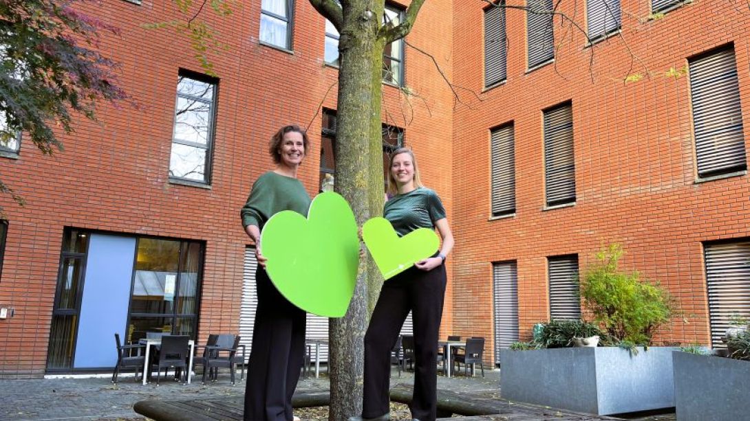 Tamara Kroll en Lieke Hettema staan op een boombank met het groene hart