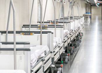 Er wandelt een man langs lege ziekenhuisbedden.