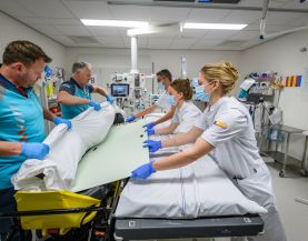 Patiënt wordt overgezet van brancard naar ziekenhuisbed