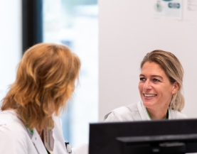 2 zorgmedewerkers met elkaar in gesprek achter pc