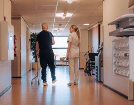 Zorgprofessional en patiënt lopen in de gang bij Roessingh